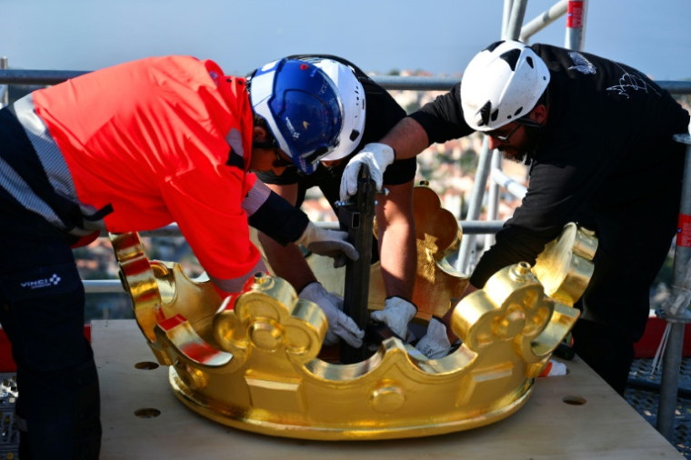Des ouvriers remettent en place la couronne dorée de la statue de la Bonne Mère, à Marseille, le 17 octobre 2025 ( AFP / Christophe SIMON )
