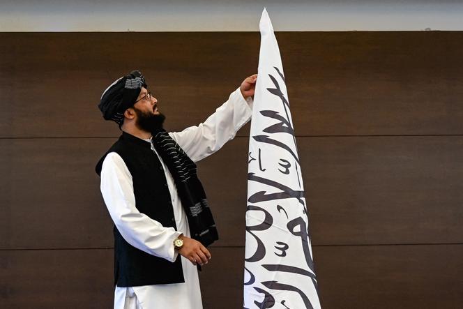 Un Afghan ajuste le drapeau taliban avant une conférence de presse du ministre afghan des affaires étrangères, Amir Khan Muttaqi, à l’ambassade d’Afghanistan à New Delhi, le 12 octobre 2025.
