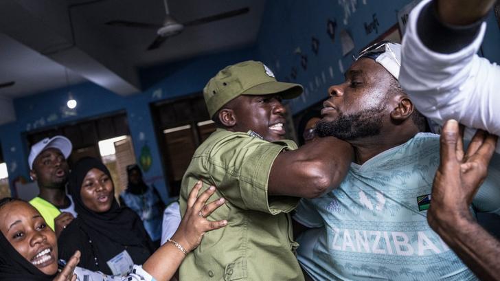 Un policier intercepte un homme dans un bureau de vote de Stone Town, le 29 octobre 2025, en Tanzanie.