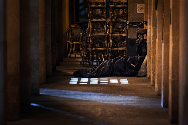 Un homme dort dans un sac de couchage à proximité d'une terrasse de café le 15 octobre 2025 à Paris