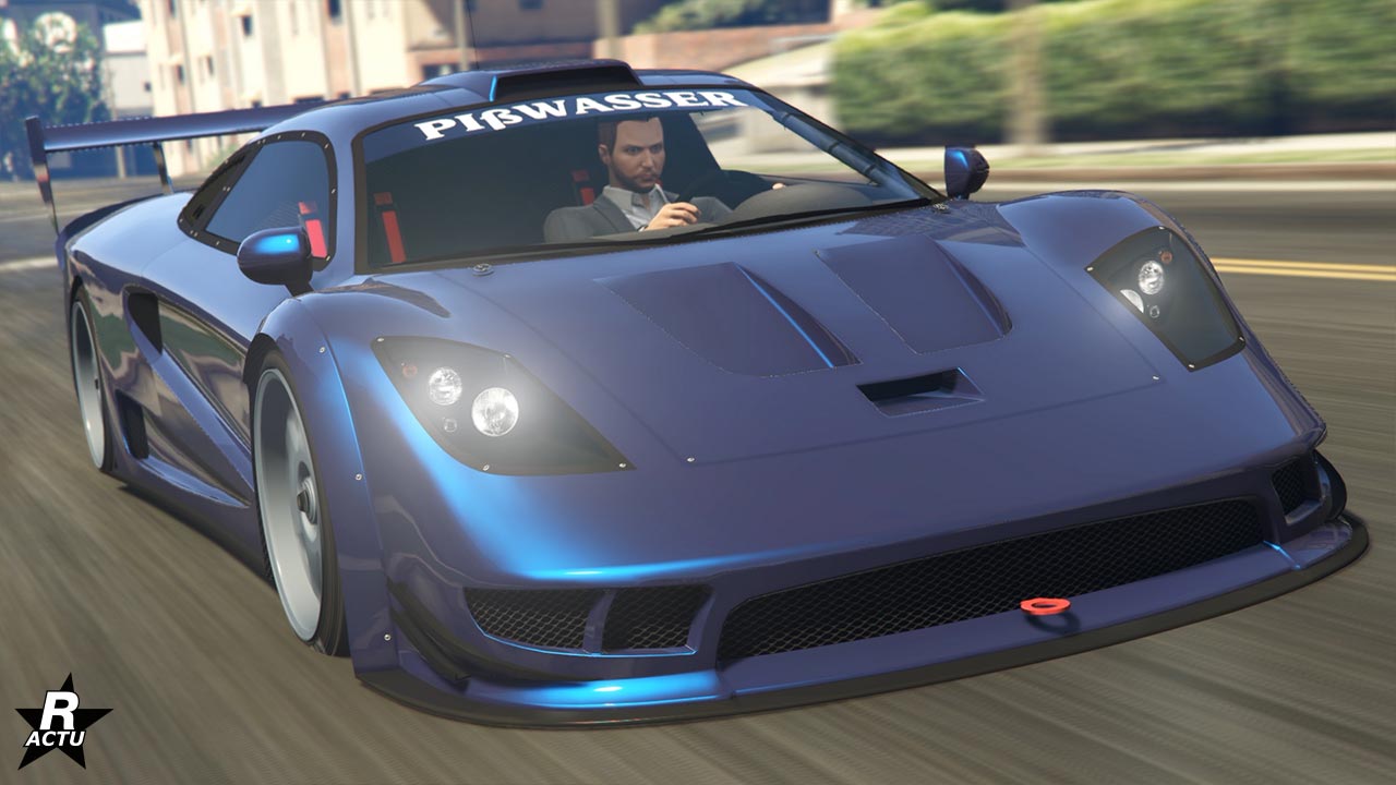 Image montrant une voiture mauve sponsorisée par “Pißwasser” où son logo est affiché en grand sur le pare-soleil. Le véhicule est la Progen Tyrus représentée en mouvement sur une route de GTA Online. La voiture a une position basse et large, typique des véhicules haute performance, avec des caractéristiques aérodynamiques comme un splitter avant et des prises d’air sur le capot.