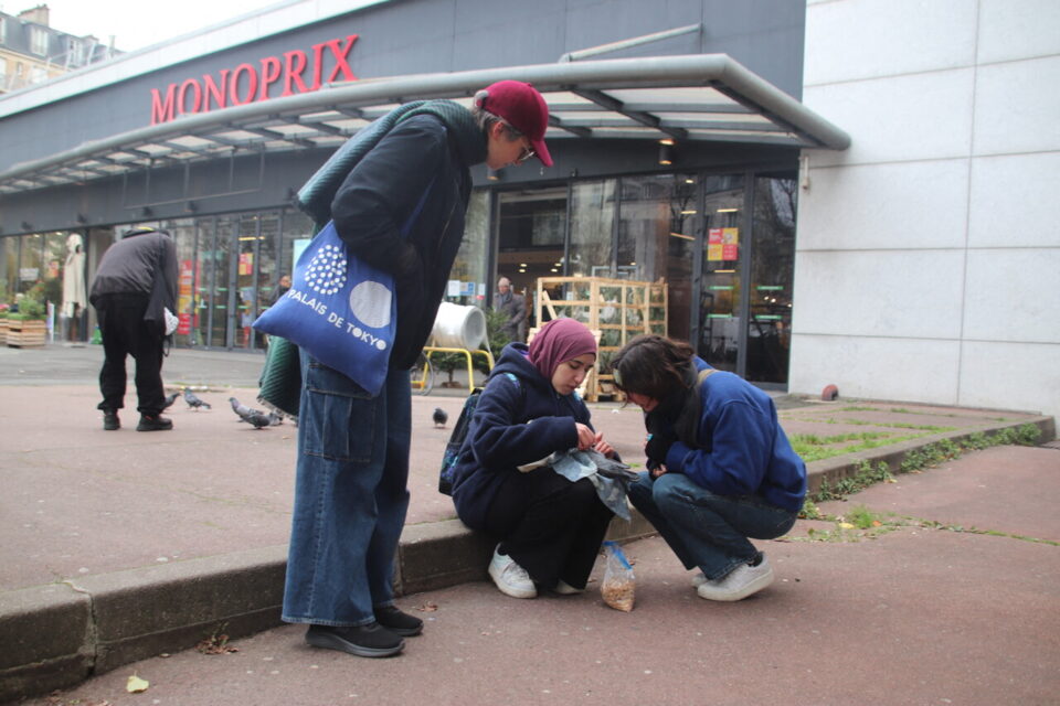 Alina et Camille regardent Maryam pendant qu'elle soigne un pigeon, avenue d'Italie à Paris.