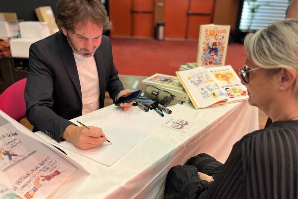 Le caricaturiste Dadou réalise un dessin en direct devant les participants.