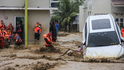 En Indonésie, des secouristes essaient d'avancer dans l'eau afin de tenter d'évacuer des habitants bloqués dans leurs maisons à Padang, dans la province de Sumatra Ouest, le 27 novembre 2025. (REZAN SOLEH / AFP)