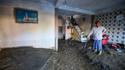 Un habitant inspecte son salon ravagé, dont le sol est recouvert de boue du fait des inondations à Meureudu, en Indonésie, le 30 novembre 2025. (CHAIDEER MAHYUDDIN / AFP)