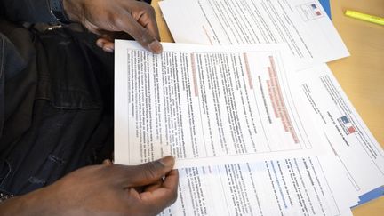 Un jeune migrant remplit sa demande de permis de séjour dans les locaux d'une association, le 27 décembre 2023 à Poitiers. (JEAN-FRANCOIS FORT / HANS LUCAS / AFP)