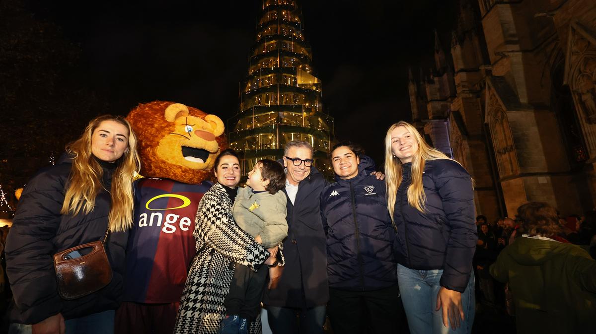 Les trois joueuses du Stade Bordelais, la danseuse étoile Mathilde Froustey et la mascotte Léo posent autour du maire, devant le sapin rallumé.