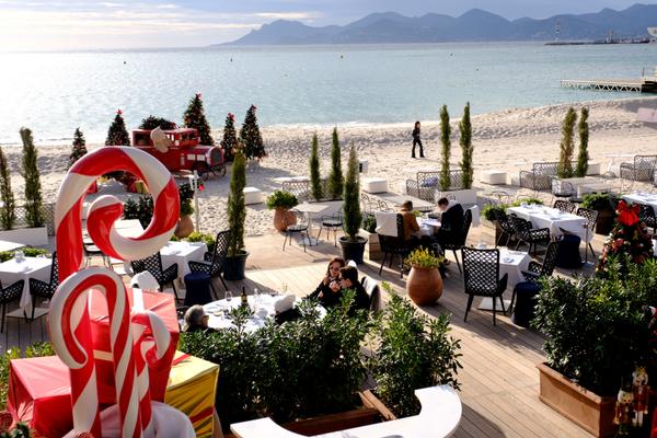 Une terrasse de restaurant de plage presque vide, où quelques chaises isolées témoignent d’une fin d’année calme et venteuse.