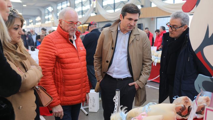 Benoît de Boysson (en manteau beige), candidat aux élections municipales de Bourg-en-Bresse et cadre Reconquête, avec ses colistiers et l'entrepreneur Christophe Feillens (en orange), au marché couvert, le 12 décembre 2025. (LAURE COMETTI / FRANCEINFO)