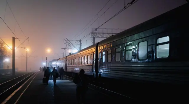 Un train et des personnes sur le quai dans le brouillard.