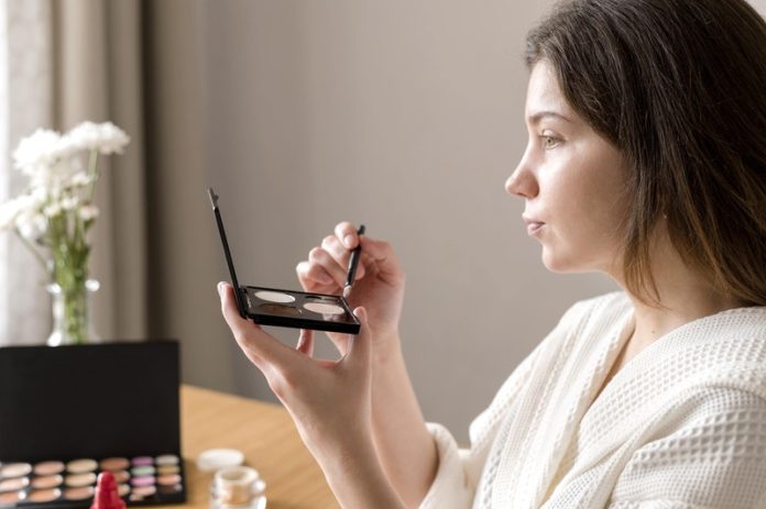 cosmétiques toxiques nanoparticules invisibles dans vos cosmétiques pailletés faut il vraiment s’inquiéter Ma Santé Une femme qui se maquille avec des cosmétiques pailletés toxiques, contaminés au titane.