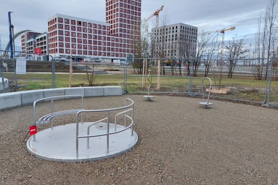 Du mobilier a déjà été installé, ci-dessus un tourniquet inclusif. Une personne en fauteuil roulant peut y prendre place au centre.