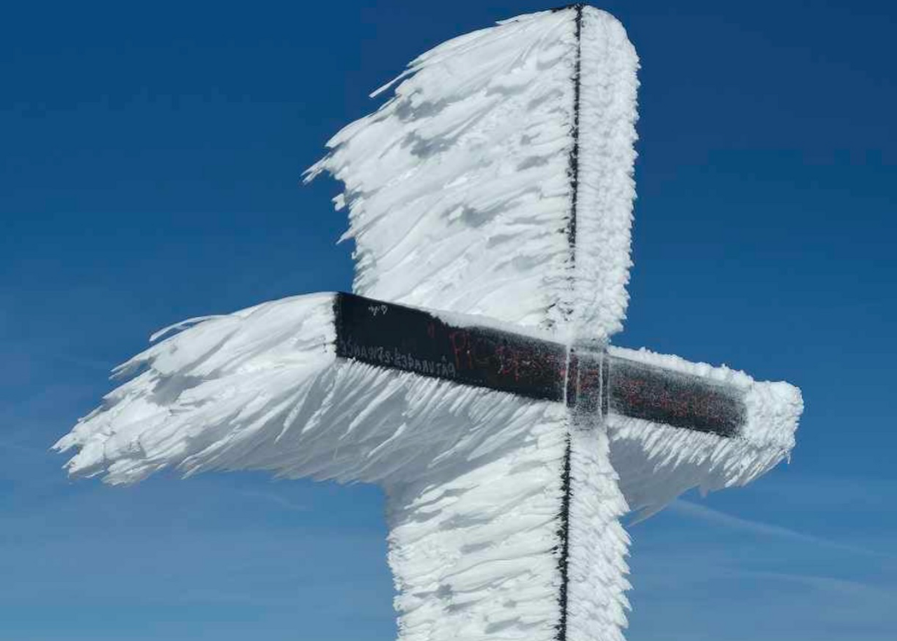 Avec le vent glacial, cette croix dans les Pyrénées se transforme en sculpture de neige