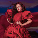 Rosalia en tenue épurée inspirée de l’esthétique de LUX, micro à la main, éclairage doré, concert d’Anvers 2026.