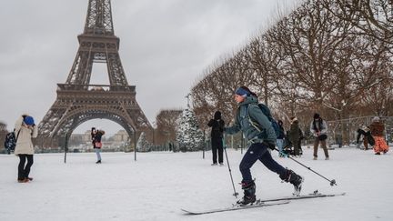 Une Parisienne se déplace en ski aux abords de la tour Eiffel, le 7 janvier 2026. (LUDOVIC MARIN / AFP)
