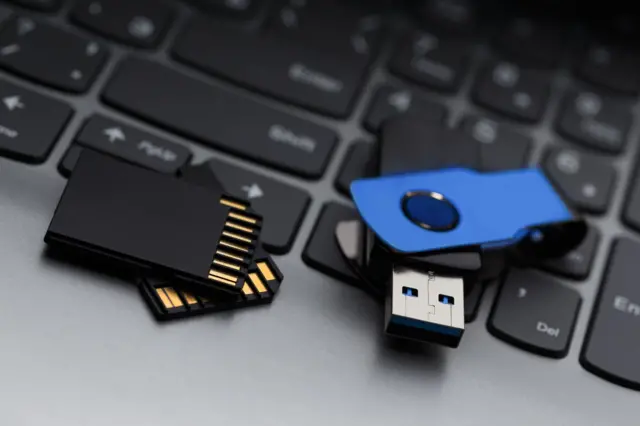 Une paire de cartes SD et une clé USB bleue sur le clavier d'un ordinateur portable