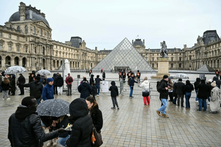 Des visiteurs devant le musée du Louvre et la pyramide conçue par l'architecte sino-américain Ieoh Ming Pei, fermés lors d'un mouvement de grève, le 12 janvier 2026 à Paris ( AFP / Martin LELIEVRE )