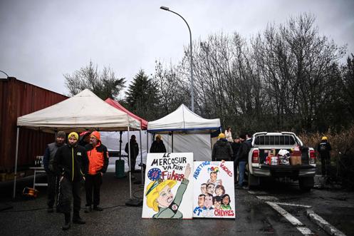 Farmers stand by boards depicting European Commission President Ursula von der Leyen as they block the access to the 