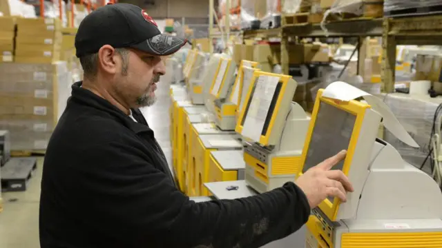 Un technicien effectue une vérification sur un kiosque de tirage photo Kodak