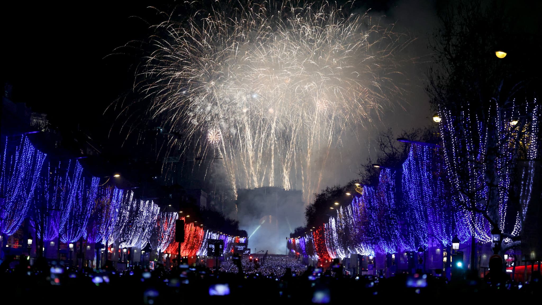 Des gens se rassemblent sur les Champs-Élysées pour assister au feu d'artifice et aux jeux de lumière lors des célébrations du Nouvel An à Paris, en France, le 1er janvier 2026.