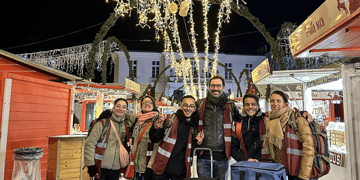 Festivités de Noël à Nantes, groupe de voyageurs souriants sous guirlandes lumineuses.