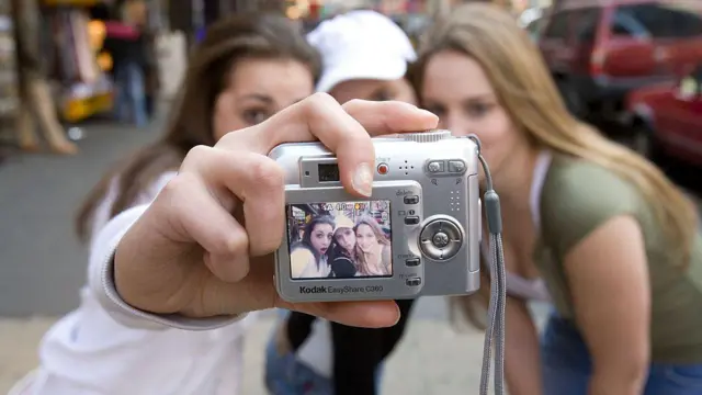 Trois adolescents prennent des selfies avec un appareil photo numérique Kodak EasyShare à Times Square (États-Unis)
