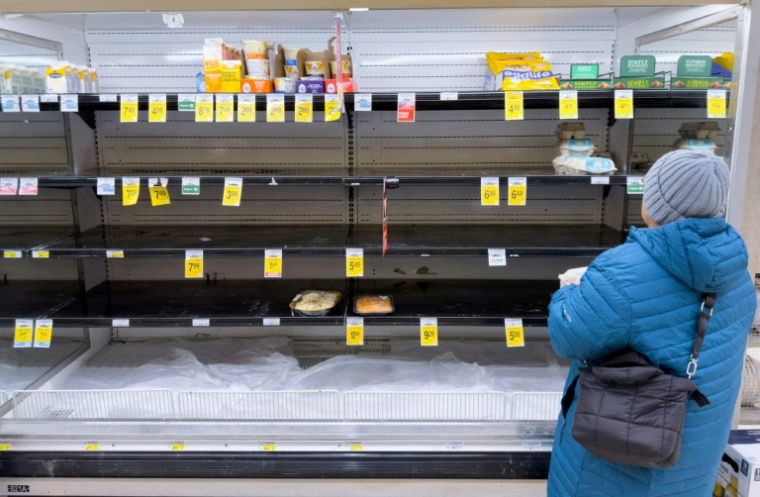 Une femme prend des œufs sur des étagères en grande partie vides, tandis que les habitants font des provisions avant l’arrivée d’un front froid prévu dans la région d’Arlington, en Virginie, le 23 janvier 2026 ( AFP / SAUL LOEB )