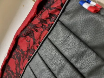 Détail du cuir, de la dentelle, et du tissu du pouf, avec une étiquette signalant la fabrication en France.