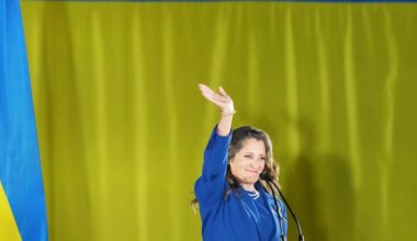 Chrystia Freeland salue la foule devant un drapeau ukrainien.