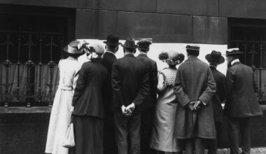Photo en noir et blanc personnes rassemblées devant un tableau blanc
