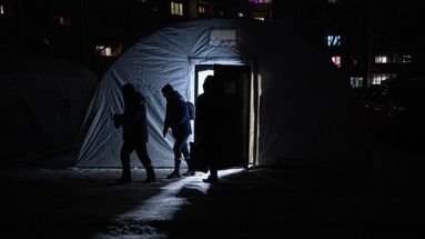 Des Ukrainiens quittent un point de ravitaillement, conçu pour faire face aux coupures d'électricité qui touchent le pays après des frappes russes ciblées, le 17 janvier 2026.