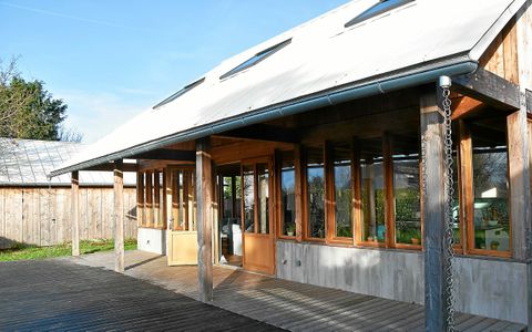 La maison est entièrement bardée de bois et couverte d’une toiture métallique.