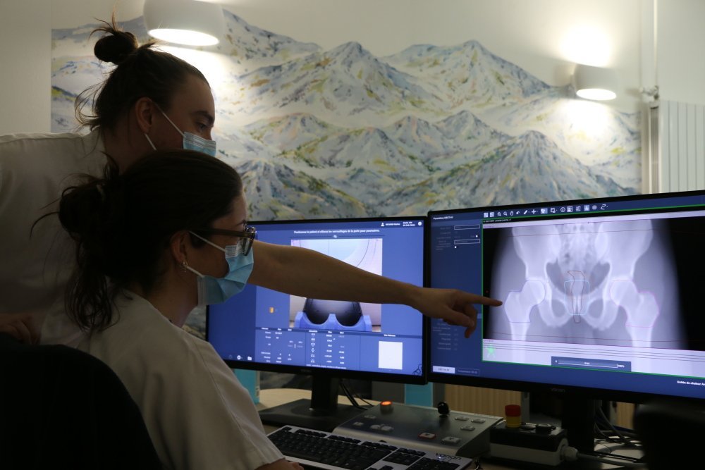Valentin Jorel et Clémentine Roussel Terrier positionnent et échangent avec le patient durant la séance. Ils vérifient les zones délimitées par l'IA qui vont être traitées, et lancent le traitement après l'accord du médecin.