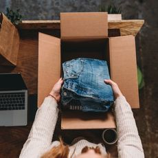 Une femme met un jean dans un carton, après l'avoir vendu en ligne.