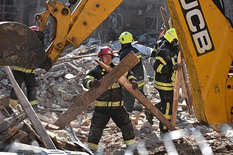 Un secouriste déblaie les décombres après une frappe russe sur un quartier résidentiel de Dnipro, en Ukraine, le samedi 25 avril 2026.