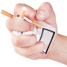 Main d’un homme écrasant des cigarettes.