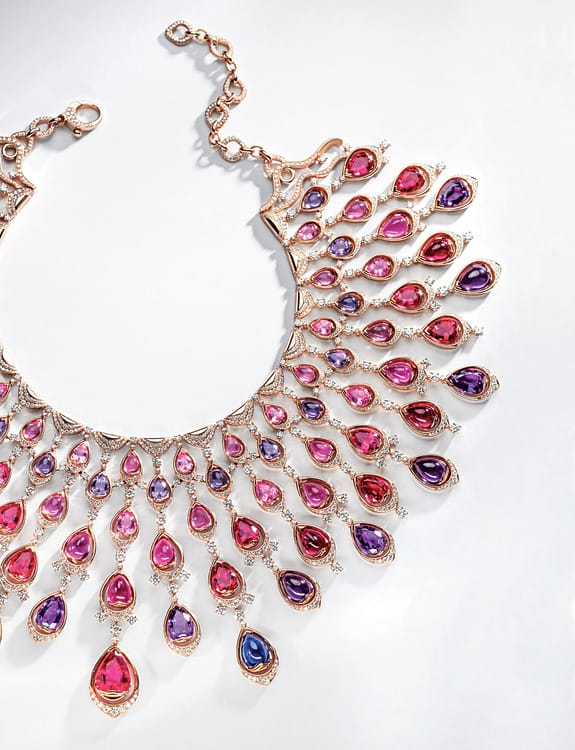 Elegant necklace with pink and purple gemstone teardrops arranged in intricate design on a white background.