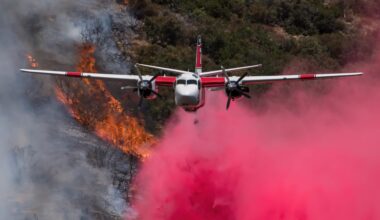 A firefighting plane drops red fire retardant.