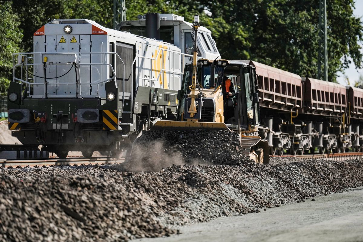 DB InfraGO freight train with locomotive and rail maintenance vehicle working on Hamburg-Berlin railway track renewal