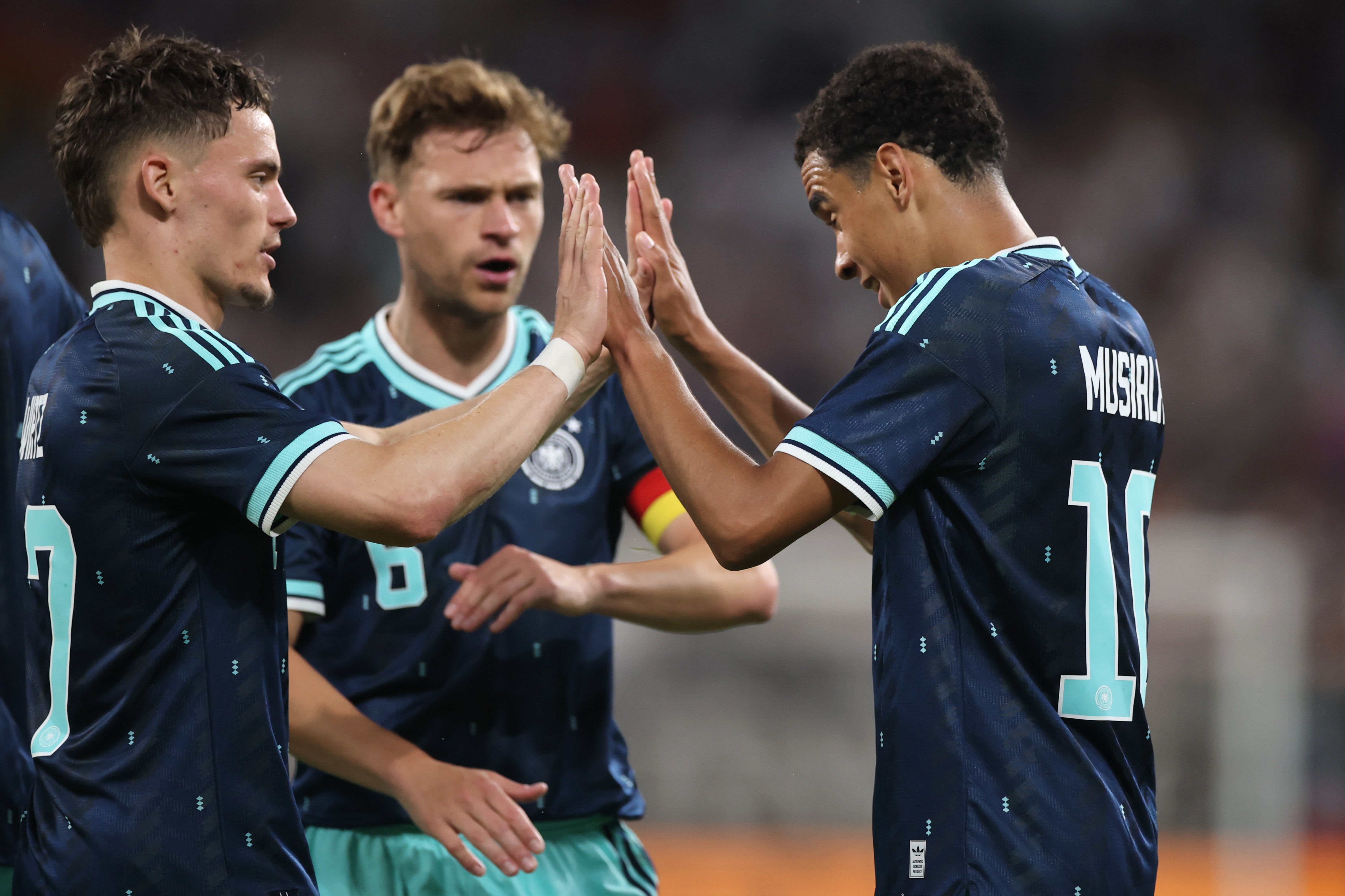 Jamal Musiala of Germany celebrates the team's fourth goal against Finland with teammates Joshua Kimmich and Florian Wirtz
