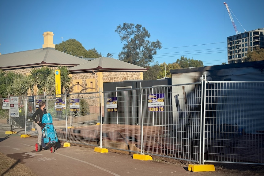 A golfer walks past temporary fencing that blocks off a building where there has been a fire