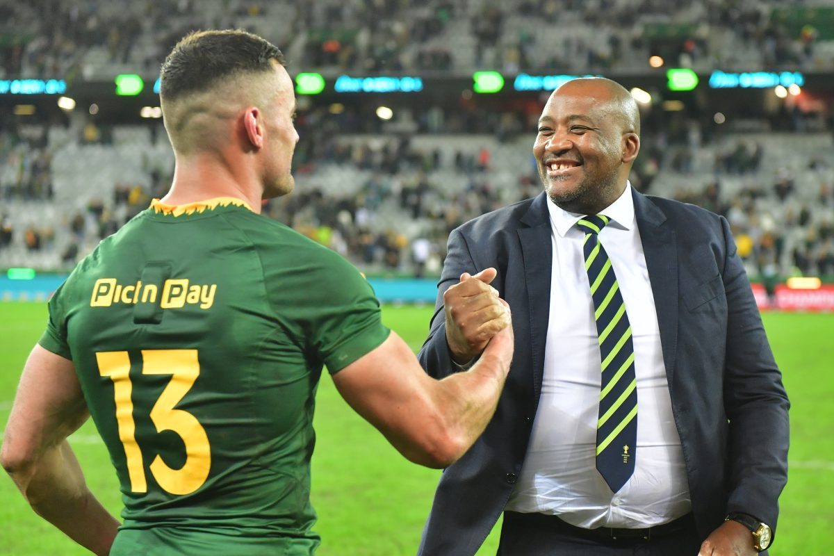 Rugby player in green jersey with Pic n Pay 13 shaking hands with a smiling man in a suit and tie