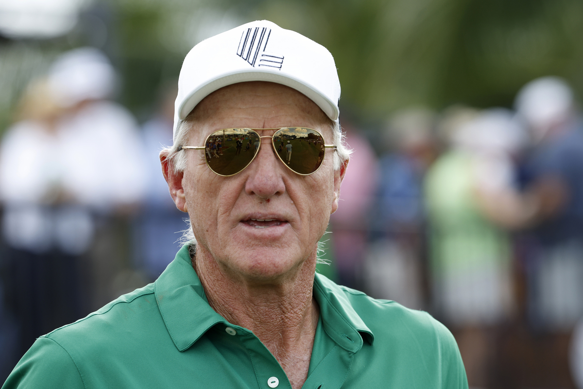 Greg Norman, CEO of LIV Golf, wearing a white cap, sunglasses, and a green polo shirt outdoors.