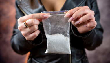 female hand holds bag with cocaine for sale, overdose danger, criminal concept