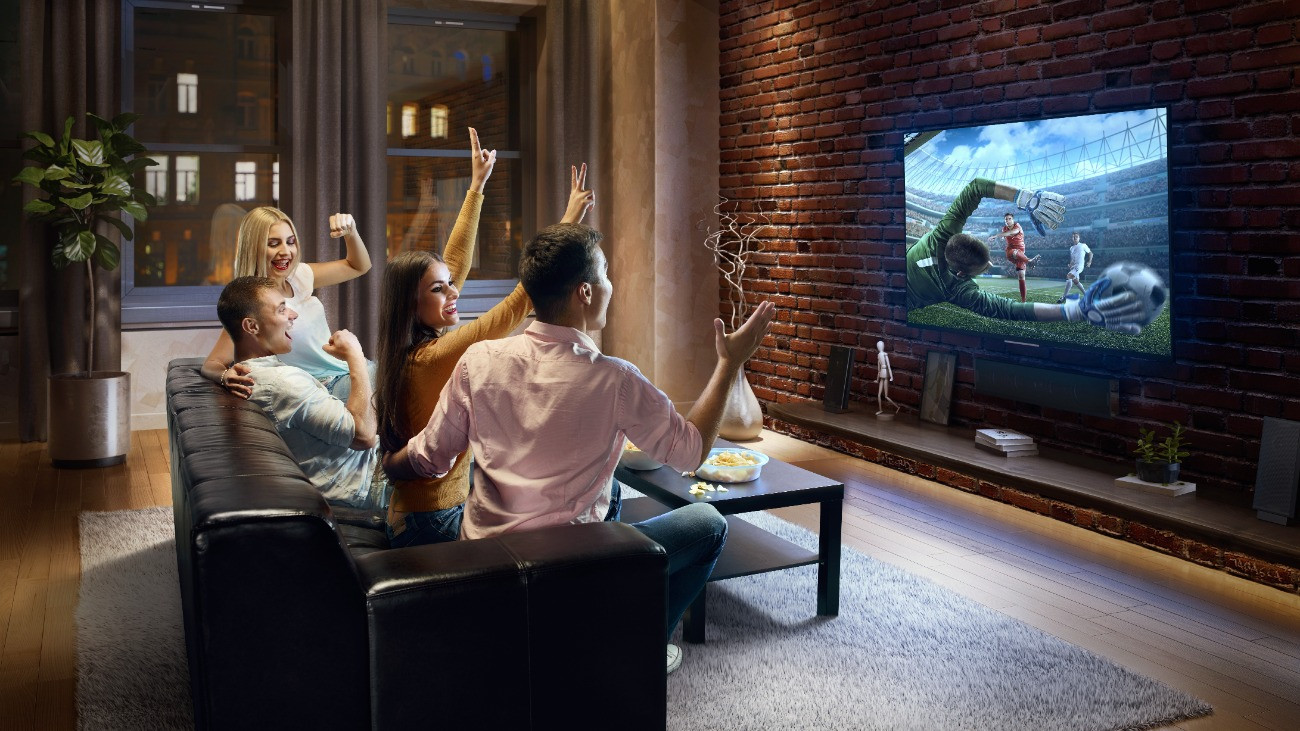 Két fiatal pár focimeccset néz a tévében.