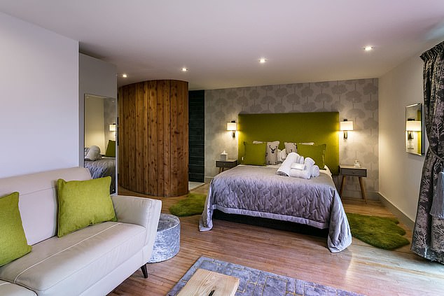 A modern styled bedroom with a sofa and an en suite wioth a green and cream colour theming