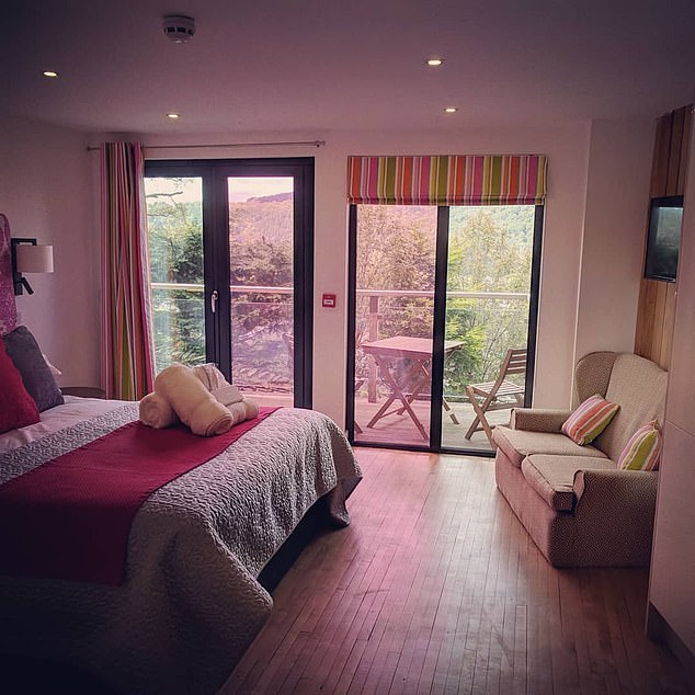 A bedroom looks out onto a picturesque balcony with a table and chairs sat outside the door