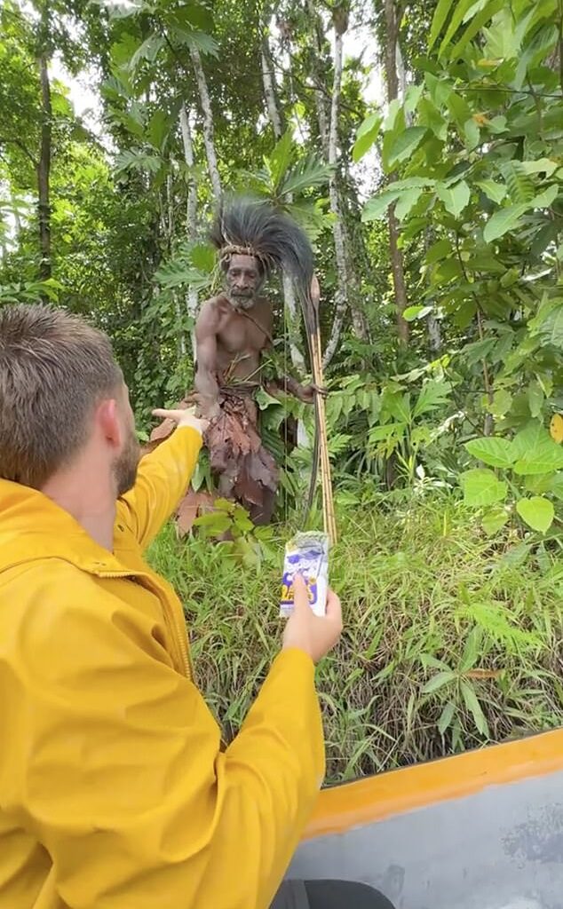 The footage shows tribesmen looking suspiciously at their visitors - with one even aiming an enormous bow and arrow towards their boat