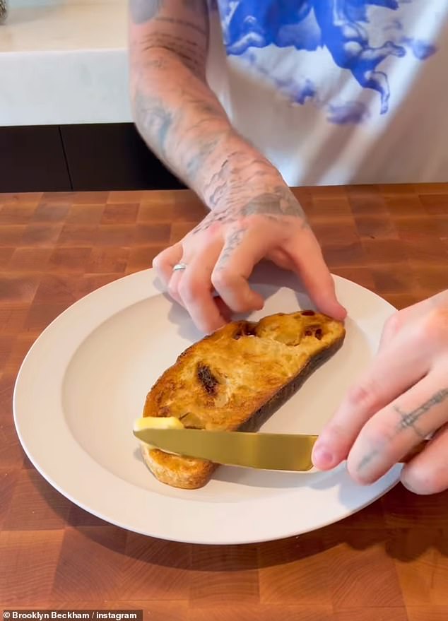 Brooklyn was seen buttering sourdough toast before spreading jam on top