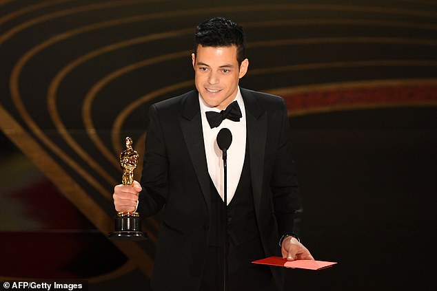 Rami chose the biggest moment of his career to confirm their romance, kissing Lucy after his name was read out as the winner of the Best Actor award (pictured)